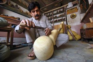 A craftsman is busy making the traditional musical instrument, Rabab, at his workshop in the Tehsil area