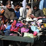 People purchase plastic footwear from a roadside handcart on Empress Road