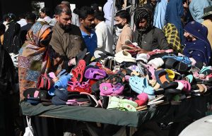 People purchase plastic footwear from a roadside handcart on Empress Road