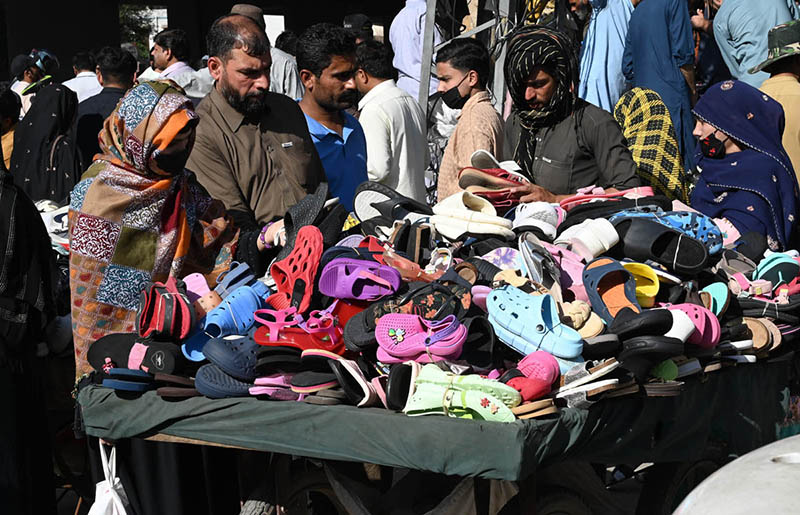 People purchase plastic footwear from a roadside handcart on Empress Road