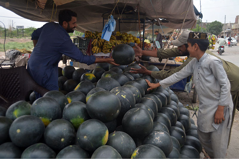 Buyers and sellers engage in the sale and purchase of watermelons in a lively and happy mood at a local market