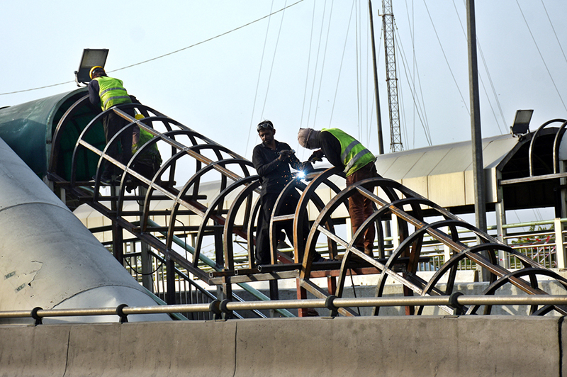A welder welds an iron frame to install a shed at the metro station on Karnal Road in the provincial capital