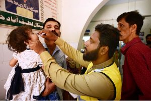 A health worker administers a polio vaccine to a child during a door-to-door vaccination campaign in at Zaryab colony faqirabad area