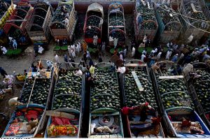 An aerial view of watermelons being auctioned as traders and farmers bargain with dealers, while shopkeepers participate in bidding at a fruit market in the provincial capital.