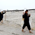 Children walk around wearing sacks over their heads to protect themselves from the rain