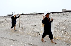Children walk around wearing sacks over their heads to protect themselves from the rain