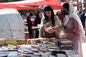 Women browse and buy old books from stall at Mall Road.