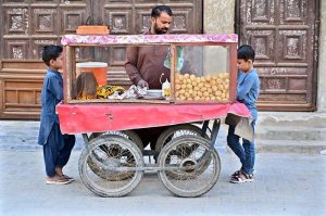 Children enjoy Gol Gappay as a street vendor sells the traditional snack at Sachal Colony.