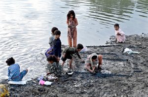 Children walk around wearing sacks over their heads to protect themselves from the rain