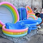 A vendor is busy filling air in plastic swimming pool at his roadside setup to attract the customers in Provincial Capital