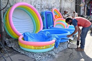 A vendor is busy filling air in plastic swimming pool at his roadside setup to attract the customers in Provincial Capital