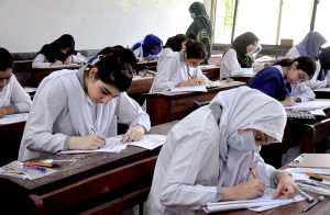 Intermediate students appear in examinations as invigilators monitor the examination process at a centre in the city.