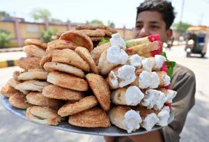 A young street vendor carries a tray of bakery items on his shoulder as he sells them on DC Office Road.