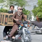 A motorcyclist on the way while covers his face with piece of cloth to protect himself from the scorching heat