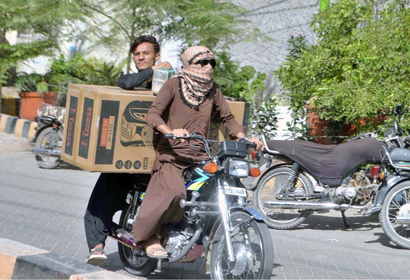 A motorcyclist on the way while covers his face with piece of cloth to protect himself from the scorching heat