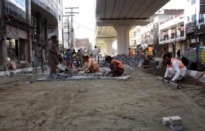 LDA workers engaged in fixing tuff tiles on the main road outside Data Darbar as part of ongoing maintenance work
