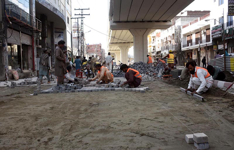 LDA workers engaged in fixing tuff tiles on the main road outside Data Darbar as part of ongoing maintenance work