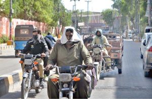 A motorcyclist on the way while covers his face with piece of cloth to protect himself from the scorching heat