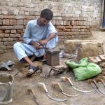 As the wheat harvesting season approaches, a man is busy preparing sickles, traditional tools used to harvest standing wheat crops