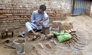 As the wheat harvesting season approaches, a man is busy preparing sickles, traditional tools used to harvest standing wheat crops