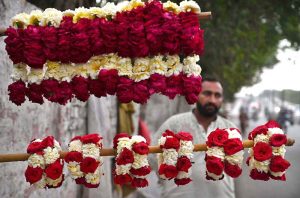 A vendor is waiting for customers to sell fresh flower hand garlands on the roadside in the provincial capital