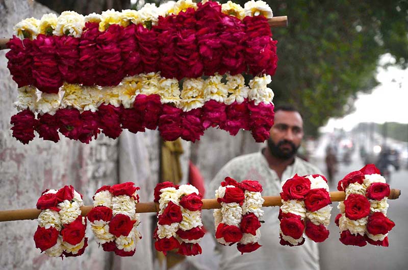 A vendor is waiting for customers to sell fresh flower hand garlands on the roadside in the provincial capital