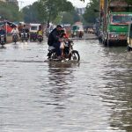 Motorcyclists passing through rain water accumulated on the road after rain that experienced the Provincial Capital