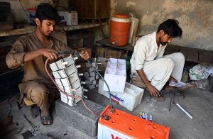 An electrician repairs old batteries at his workplace on Railway Road as the world observes International Labour Day.