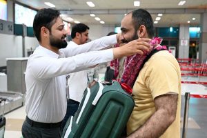 Relative place flower garland around woman pilgrim before departure of the first Hajj flight from Sialkot Airport