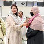 Relative place flower garland around woman pilgrim before departure of the first Hajj flight from Sialkot Airport