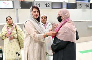 Relative place flower garland around woman pilgrim before departure of the first Hajj flight from Sialkot Airport