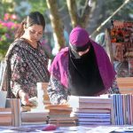 Women are busy selecting and purchasing old books from a stall at Frere Hall