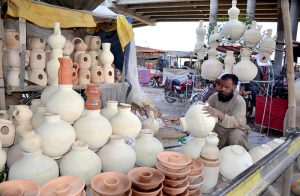 A vendor arranges traditional clay pitchers, as demand for earthen water pots rises with the changing weather conditions in the city.