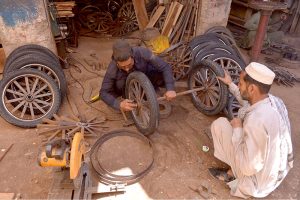 A wheelwright repairs cart wheels at a workshop on Phandu Road on the eve of International Labour Day.