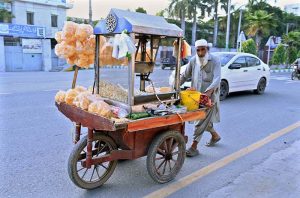 An elderly street hawker pulls his hand cart filled with food Items to earn for livelihood.