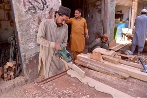 A carpenter levels wood to craft wooden frames at a workshop on Phandu Road, reflecting skilled craftsmanship and hard work on the eve of International Labour Day.