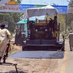 Workers repair a section of Srinagar Highway by laying asphalt during ongoing road maintenance work