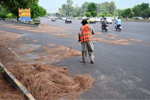 A CDA sanitary worker is busy cleaning Faisal Avenue after the late-night storm in the Federal Capital