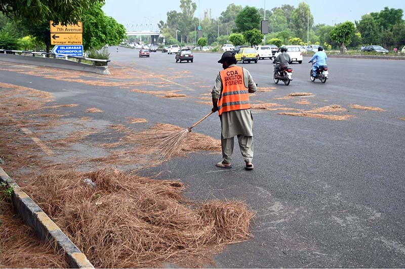 A CDA sanitary worker is busy cleaning Faisal Avenue after the late-night storm in the Federal Capital