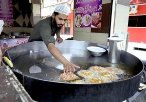 A cook prepares traditional Chapli Kabab in a large wok at Banni Chowk to attract customers