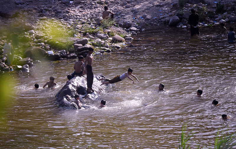 Children bathe in the water of Korang Nullah to cool off during intense hot weather, as soaring temperatures continue to affect daily life in the city