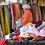 A woman browses colorful stoles at a stall in Sunday Bazaar