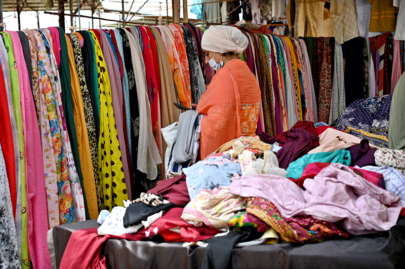 A woman browses colorful stoles at a stall in Sunday Bazaar