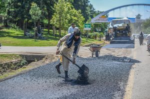 Workers repair a section of Srinagar Highway by laying asphalt during ongoing road maintenance work