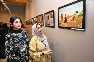A student keenly observe a photo in photo and painting exhibition organized by the Department of Arts and Design at Zubaida Agha Art Gallery in connection with Labour Day.