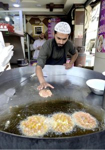 A cook prepares traditional Chapli Kabab in a large wok at Banni Chowk to attract customers
