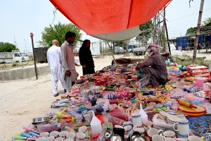 A woman browses colorful stoles at a stall in Sunday Bazaar