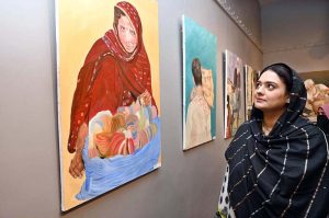 A student keenly observe a photo in photo and painting exhibition organized by the Department of Arts and Design at Zubaida Agha Art Gallery in connection with Labour Day.