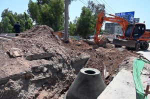 Workers construct a brick manhole inside a trench during ongoing drainage and sewerage development work along a roadside in the city
