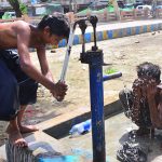 Youngsters cool off under water from a hand pump during hot weather in the city
